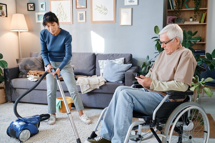 senior old man using wheelchair talking housemaid who cleaning room he giving her instructions before ndis cleaning services